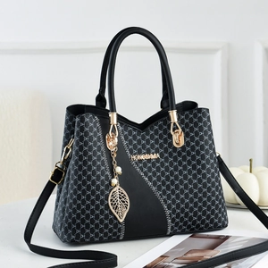 Fashionable black tote bag with DH pattern and gold logo in a stylish room setting