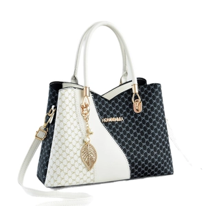 Chic black and white monogrammed handbag with gold hardware and leaf pearl pendant