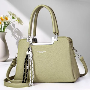 Detail of pistachio green pebble leather handbag with silver hardware and pendant