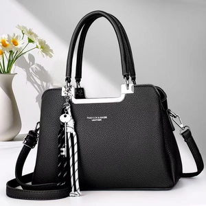 Detail of black pebbled leather handbag with silver hardware and chic woven charm
