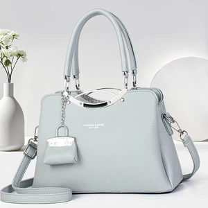 Detailed macro shot of lychee grain leather texture and elegant silver handle on a tote bag