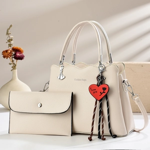 Fashionable beige tote bag set with wavy edge and heart charm shown in a minimalist setting