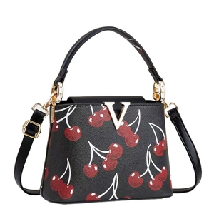 Black cherry print handbag with gold V-clasp and adjustable shoulder strap, front view