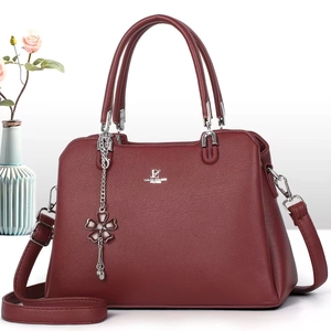 Detail of burgundy lychee grain leather tote bag with silver logo and floral charm