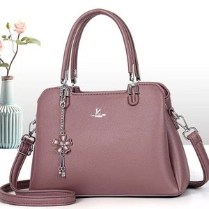 Close-up of pink pebbled leather handbag with silver logo and floral charm detail