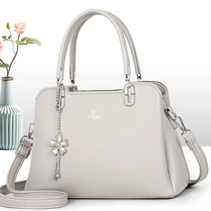 Detail of light gray lychee grain leather handbag with silver flower charm and long strap