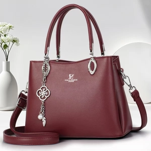 Detail of burgundy crossbody bag with silver hardware and elegant decorative charms