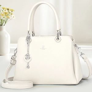 Detail of cream leather handbag with heart pendant and adjustable strap