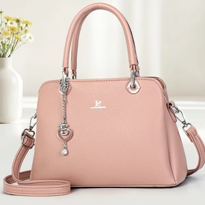 Detailed view of pink faux leather handbag with silver logo and heart chain charm