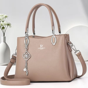 Elegant terracotta leather handbag with floral metal charm and adjustable shoulder strap