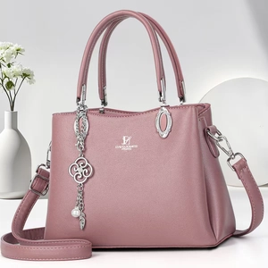 Close-up of pebble leather texture and floral metal charm on this pink crossbody bag