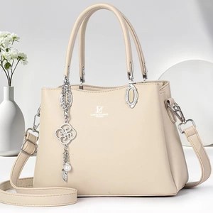 Detailed macro view of beige lychee texture leather handbag with pearl clover charm