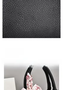 Detail of black litchi grain leather handbag with decorative floral silk scarf handle