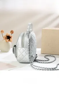 Detailed side view of silver quilted mini backpack with metal chain and leather straps