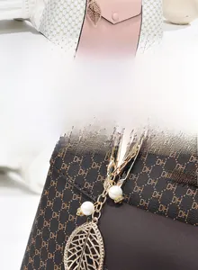 Détail de sacs à main monogramme avec breloque feuille en métal et chaîne perle