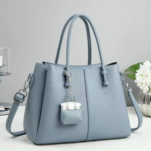 Close-up of light blue lychee pattern leather tote bag with silver hardware and mini charm