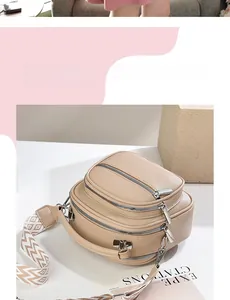 Detailed view of beige crossbody bag with triple zippers and geometric pattern wide strap