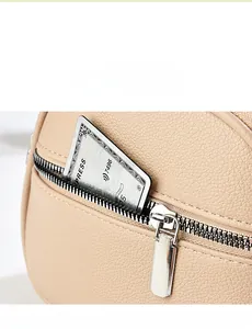 Detail of beige pebbled leather handbag featuring a smooth silver zipper and back pocket