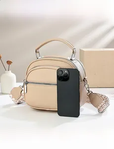 Detailed comparison of beige multi-layer crossbody bag size against a smartphone
