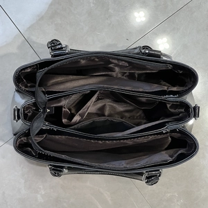 Detail view of the black tote bag showing three internal compartments and zippers