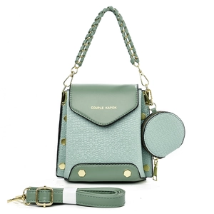 Close-up of light green square bag with woven texture, round coin purse, and gold hardware