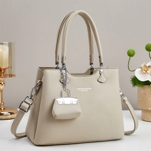 Beige pebble leather tote bag with crossbody strap and small charm accessory