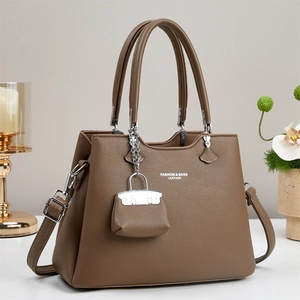 Brown faux leather handbag with litchi texture detail and mini bag charm accessory