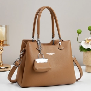 Detail of brown litchi pattern leather tote bag with fashion text and mini bag charm