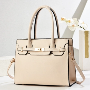 Detailed view of beige textured leather handbag with gold twist lock and shoulder strap
