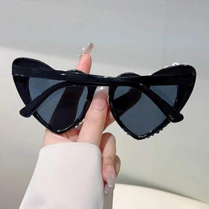 Gros plan sur des lunettes de soleil noires en forme de cœur avec perles élégantes