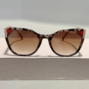 Close-up of leopard cat eye sunglasses with red corner accents and brown gradient lenses