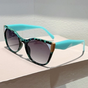 Detailed side view of green tortoiseshell sunglasses with blue temples on pink pedestal