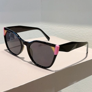 Close-up of cat-eye sunglasses with black glossy frames and pink orange accents