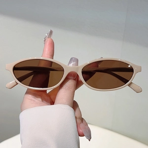 Close-up of retro oval beige sunglasses with brown tinted lenses in hand