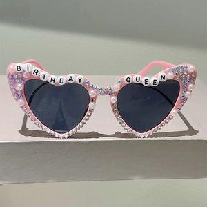Détail de lunettes d'anniversaire roses en forme de cœur avec perles et lettrage festif