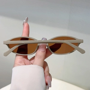 Detail shot of vintage oval beige sunglasses frame with deep amber tinted lenses