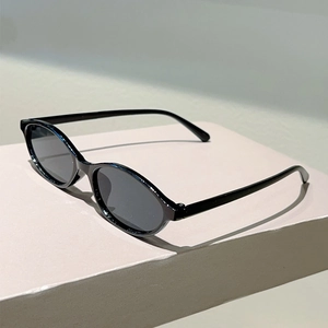 Detail shot of vintage black oval sunglasses on a minimalist stone display stand