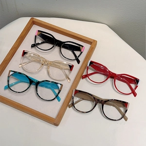 Cat-eye anti-blue light glasses frame in multiple colors on a wooden tray