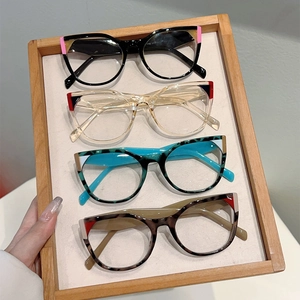 Close-up of four stylish cat-eye anti-blue light glasses in varied colors on a wooden tray