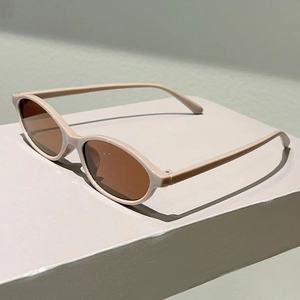 Detail view of oval cream resin frames with brown lenses on a minimalist platform
