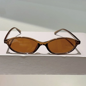 Detail view of vintage amber brown sunglasses with retro oval frame on a white podium