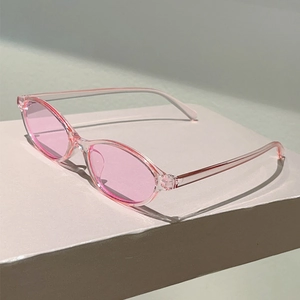 Close-up of pink transparent oval sunglasses on a minimalist white stone pedestal