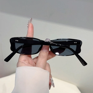 Detail of black rectangular sunglasses with silver metal rivets on a glossy frame
