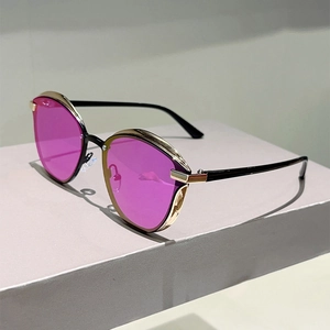 Detail view of cat eye sunglasses featuring gold metal frames and pink purple lenses