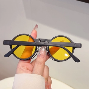 Detailed close-up of retro round matte black sunglasses with vibrant yellow tinted lenses