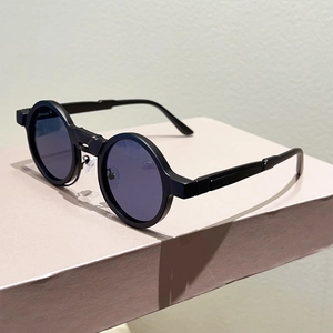 Close-up of matte black round frame sunglasses with dark lenses on a pedestal