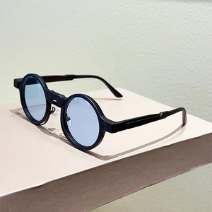 Detail view of round retro sunglasses with matte black frames and light blue lenses