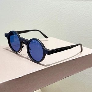 Detail of retro round sunglasses with matte black frames and blue lenses on a pink surface
