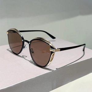 Detailed view of cat eye sunglasses with black frame, gold metal accents and brown lenses