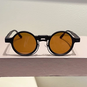 Detail of round steampunk sunglasses with amber lenses and thick matte black frames